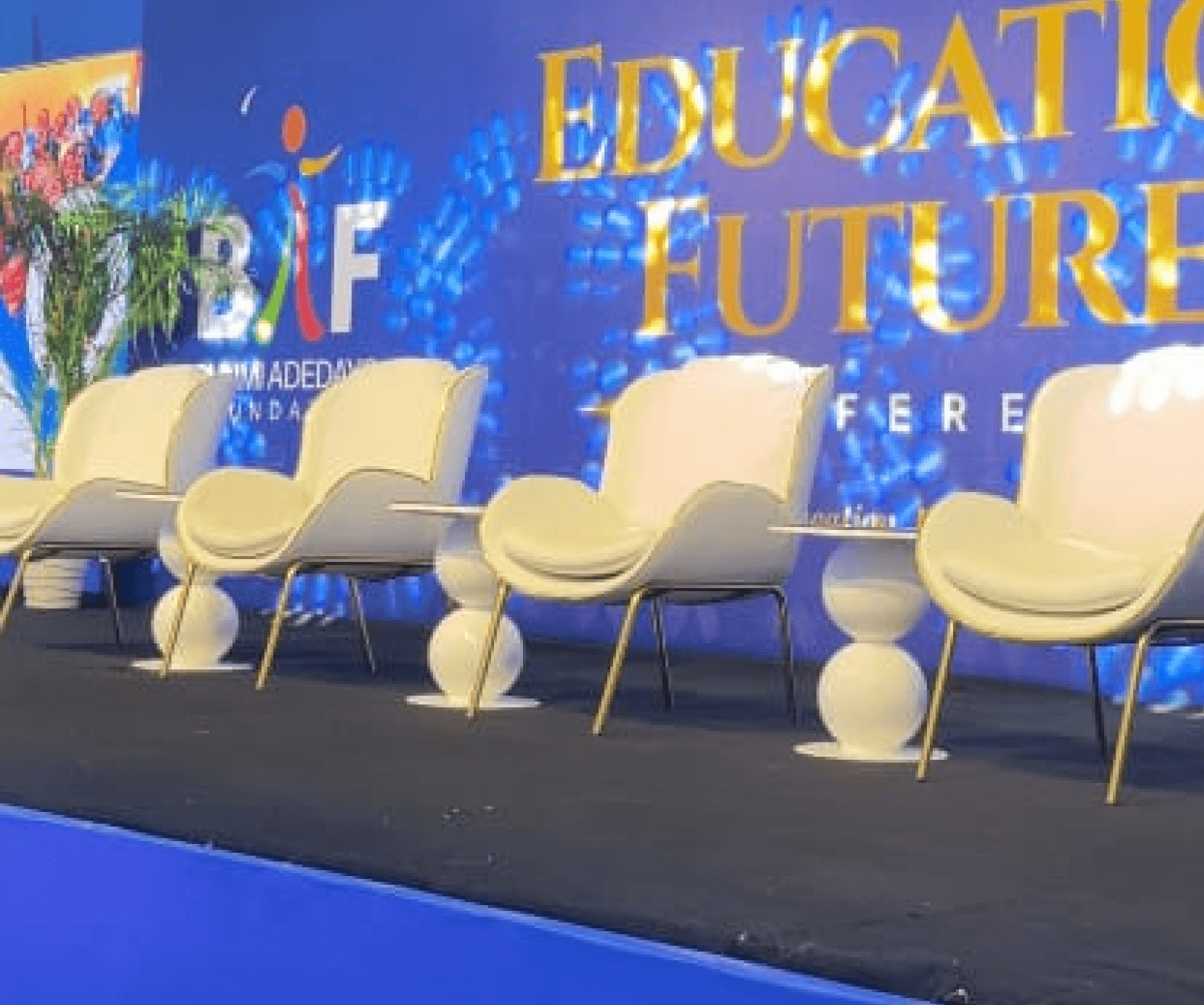 Cream chairs on stage in front of the Education Futures backdrop
